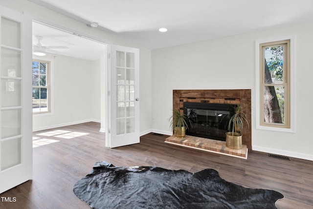 living room featuring wood finished floors, a healthy amount of sunlight, visible vents, and baseboards