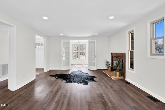 workout room featuring french doors, visible vents, dark wood-style flooring, and a fireplace with raised hearth