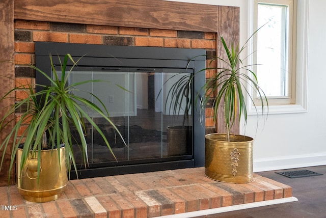 details featuring a glass covered fireplace, baseboards, and visible vents