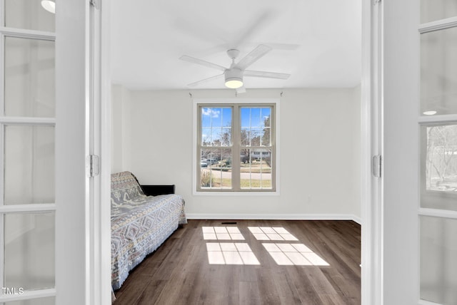 sitting room with baseboards, wood finished floors, and a ceiling fan