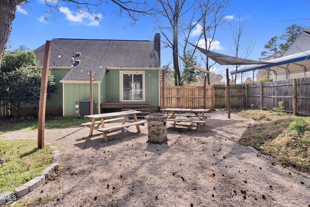 back of house with central air condition unit, roof with shingles, a chimney, and fence