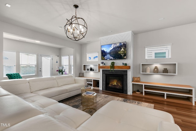 living room with a glass covered fireplace, a notable chandelier, and wood finished floors