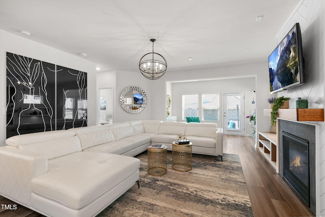 living area featuring a notable chandelier, a glass covered fireplace, and wood finished floors