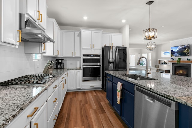 kitchen featuring blue cabinetry, a sink, white cabinets, under cabinet range hood, and appliances with stainless steel finishes