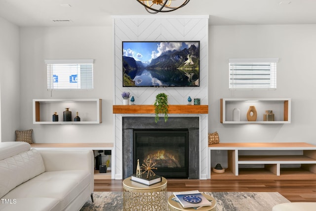 living area featuring wood finished floors, visible vents, and a large fireplace