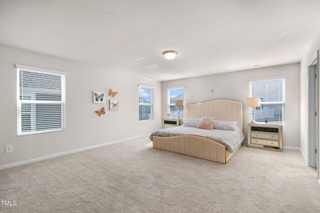 bedroom featuring multiple windows, baseboards, and light carpet