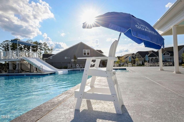 pool featuring a patio area, a water slide, and fence