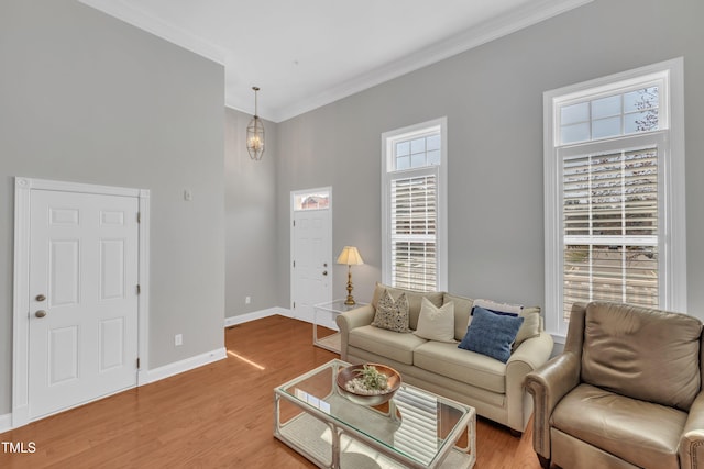 living room featuring baseboards, an inviting chandelier, crown molding, and light wood finished floors