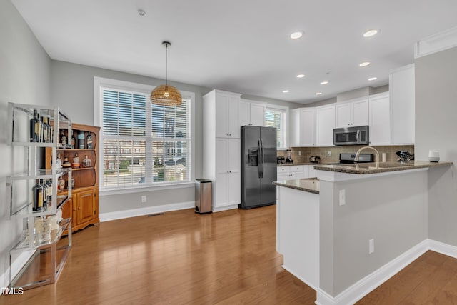 kitchen with dark stone counters, white cabinets, stainless steel microwave, tasteful backsplash, and black fridge