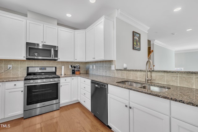 kitchen with a sink, tasteful backsplash, light wood-style floors, and appliances with stainless steel finishes