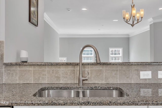 kitchen featuring a sink, stone countertops, pendant lighting, and crown molding