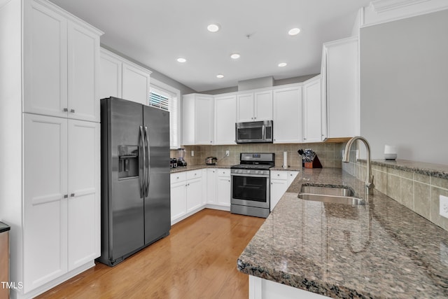 kitchen featuring a sink, light wood-style floors, backsplash, and stainless steel appliances