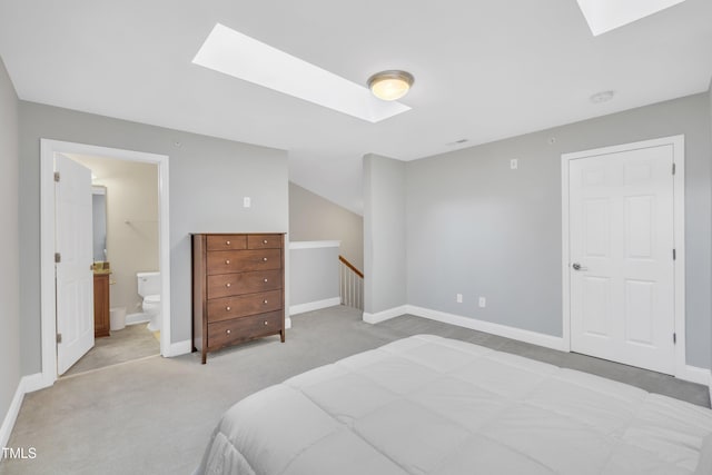 bedroom with baseboards, light carpet, ensuite bath, and a skylight