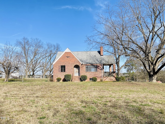 view of front of home featuring brick siding, a chimney, and a front yard