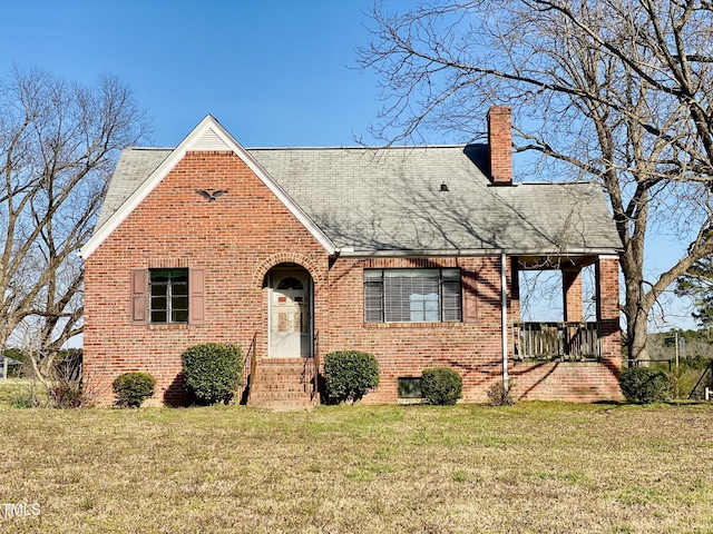 view of front of property featuring brick siding, a chimney, and a front lawn