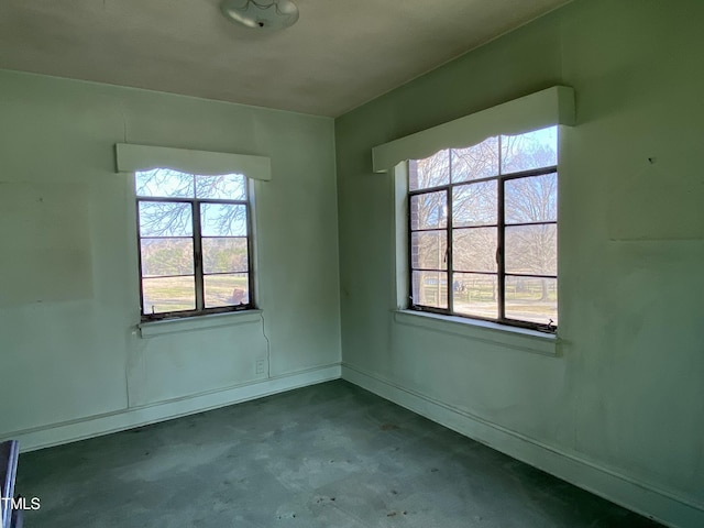 unfurnished room featuring baseboards and concrete flooring