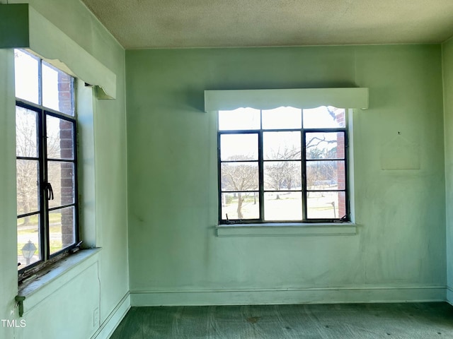 unfurnished room featuring baseboards, plenty of natural light, and a textured ceiling