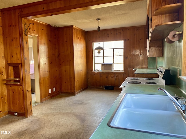 kitchen with wooden walls, range with electric cooktop, a sink, a textured ceiling, and decorative light fixtures