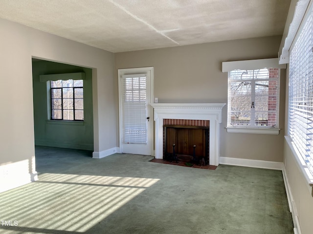 unfurnished living room featuring a textured ceiling, a fireplace, baseboards, and carpet