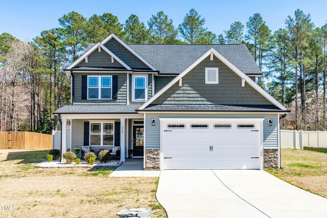 craftsman house with stone siding, driveway, and fence