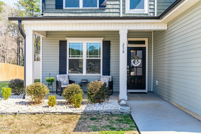 property entrance with a porch and fence