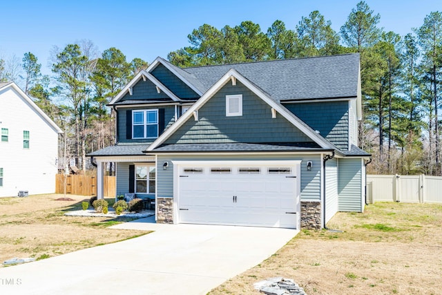 craftsman-style home featuring stone siding, fence, roof with shingles, concrete driveway, and a garage