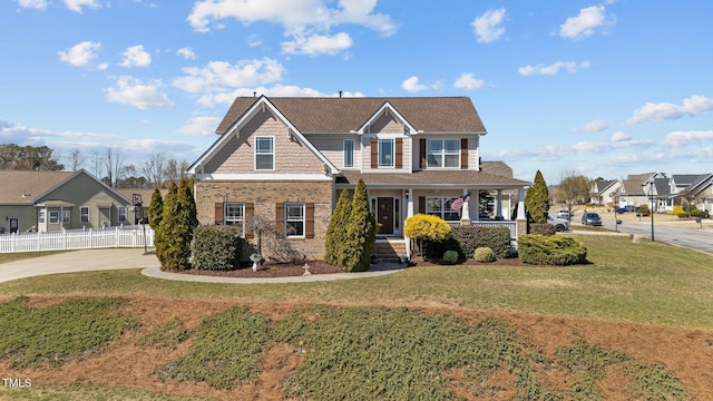 view of front of house featuring driveway, a front lawn, a porch, fence, and brick siding