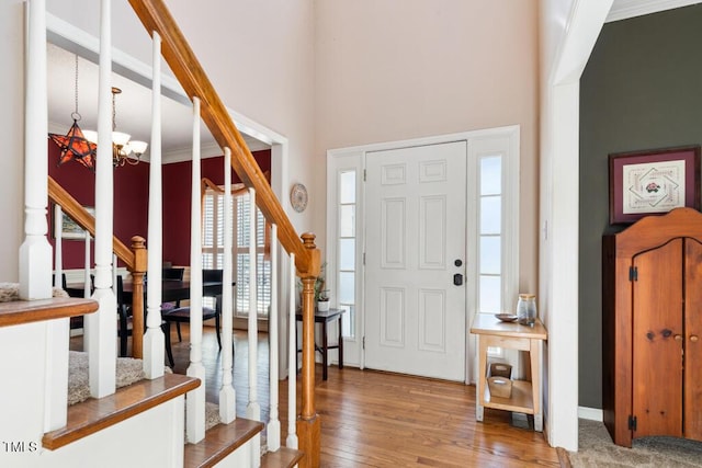 entryway with stairs, an inviting chandelier, and wood finished floors