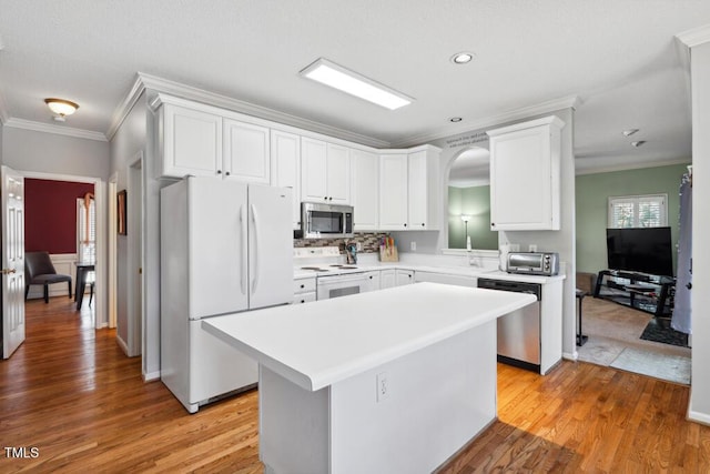 kitchen featuring light wood finished floors, appliances with stainless steel finishes, a center island, and crown molding