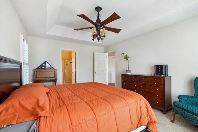 bedroom with connected bathroom, ceiling fan, light colored carpet, a textured ceiling, and a raised ceiling