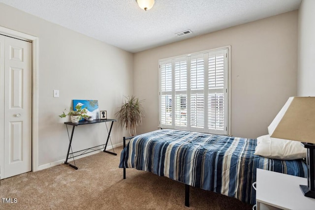 bedroom with visible vents, carpet floors, a textured ceiling, and baseboards