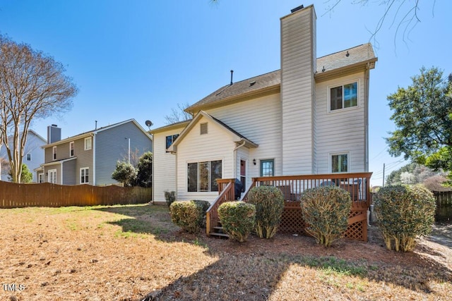 back of house featuring fence, a chimney, and a wooden deck