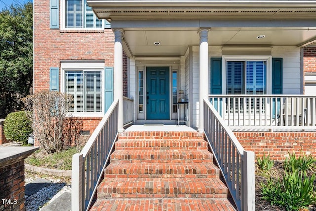 entrance to property with brick siding, crawl space, and covered porch