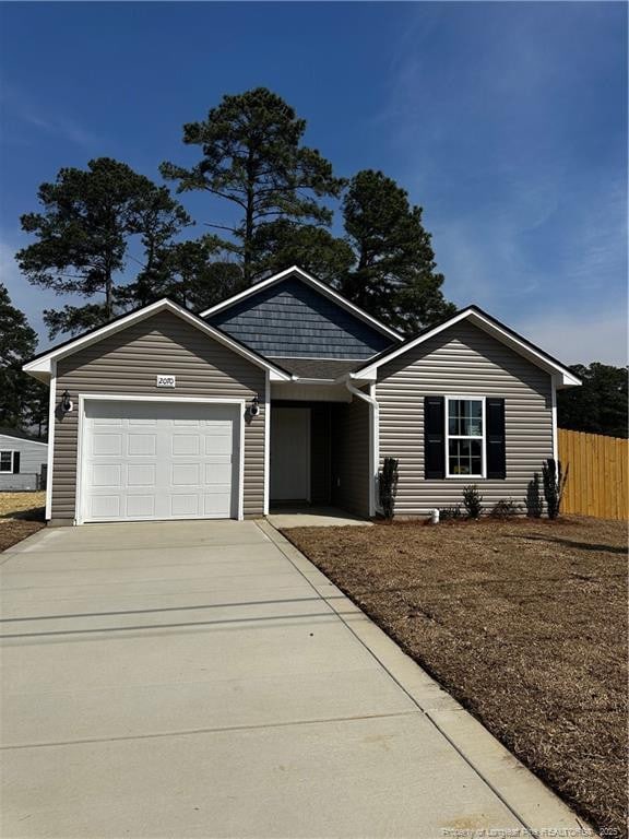 single story home featuring concrete driveway, an attached garage, and fence