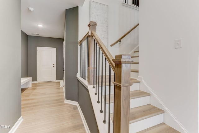 staircase with visible vents, baseboards, and wood finished floors