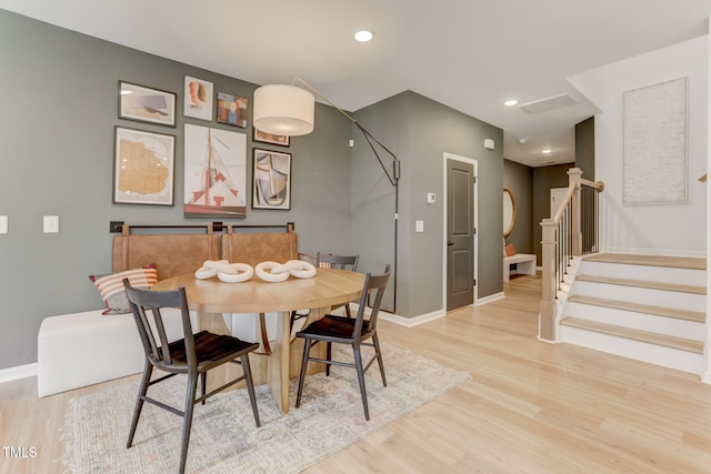 dining area with light wood finished floors, stairs, and baseboards