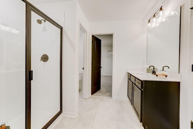 full bath with vanity, baseboards, a stall shower, a spacious closet, and toilet