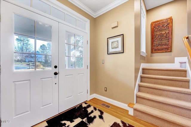 foyer featuring visible vents, baseboards, light wood-type flooring, stairs, and ornamental molding