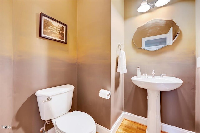 bathroom featuring toilet, wood finished floors, and baseboards