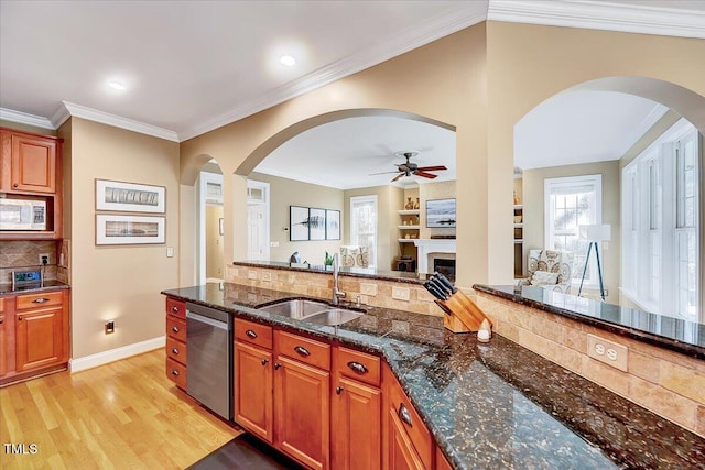 kitchen with white microwave, open floor plan, dishwasher, light wood-style flooring, and a sink