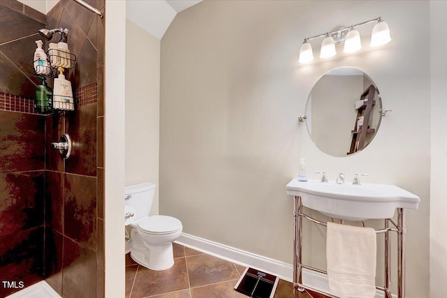 full bathroom featuring tile patterned flooring, tiled shower, toilet, and baseboards