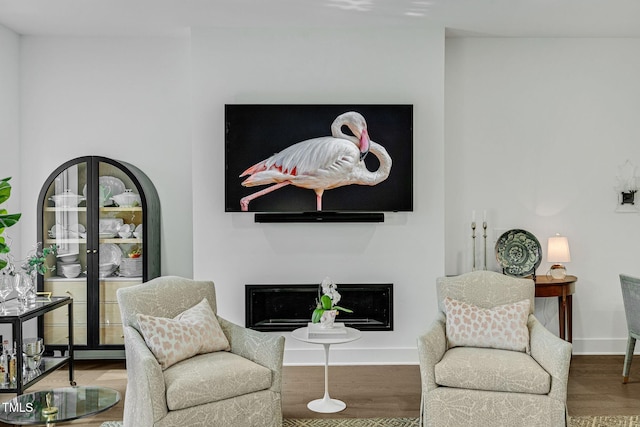 living area featuring a fireplace, wood finished floors, and baseboards