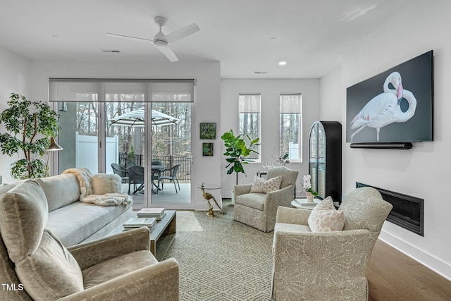 living area with a ceiling fan, wood finished floors, a healthy amount of sunlight, and visible vents