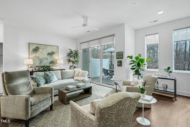 living area with hardwood / wood-style flooring, plenty of natural light, a ceiling fan, and visible vents