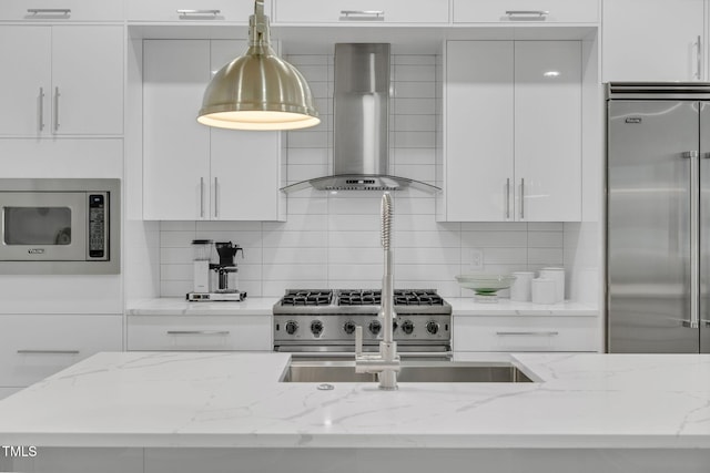 kitchen featuring white cabinets, wall chimney exhaust hood, and built in appliances