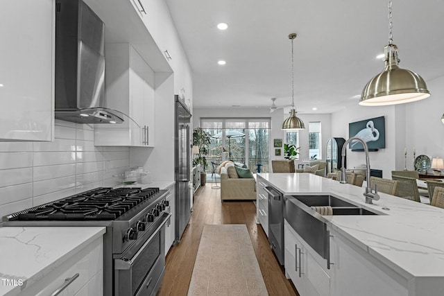 kitchen featuring wall chimney range hood, high quality appliances, dark wood-style floors, and open floor plan