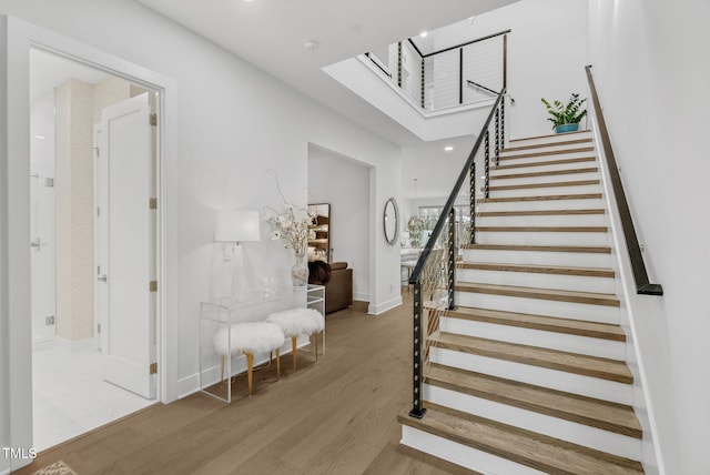 staircase with a skylight, wood finished floors, and baseboards