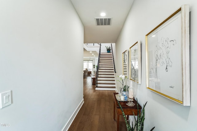 hallway with stairway, baseboards, visible vents, and dark wood-style flooring