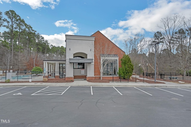 view of building exterior with uncovered parking and fence