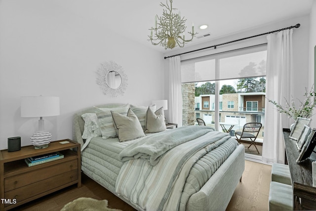 bedroom with visible vents, an inviting chandelier, and wood finished floors